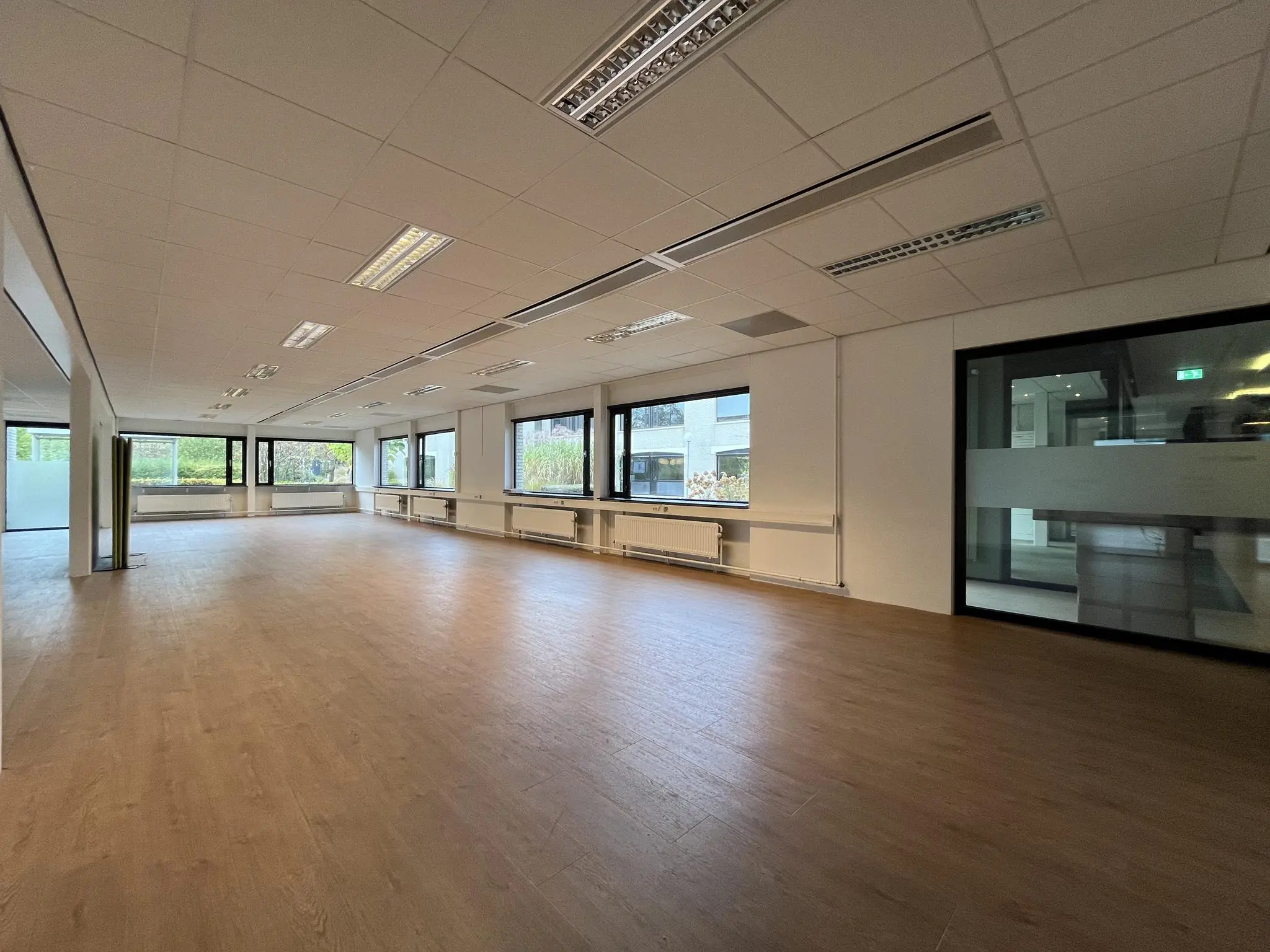 Licht en ruim leeg kantoor met houten vloer aan de Burgemeester Verderlaan.